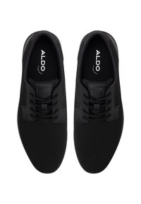 Czarne trampki wykonane z siateczkowego materiału, z okrągłymi sznurówkami, teksturowanym czubkiem i logo na wkładce. Smukły design i kształt.