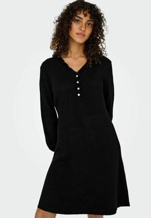 Robe tricotée noire à manches longues, décolleté en V, col volanté et cinq boutons décoratifs. Texture douce, forme évasée, longueur genou.