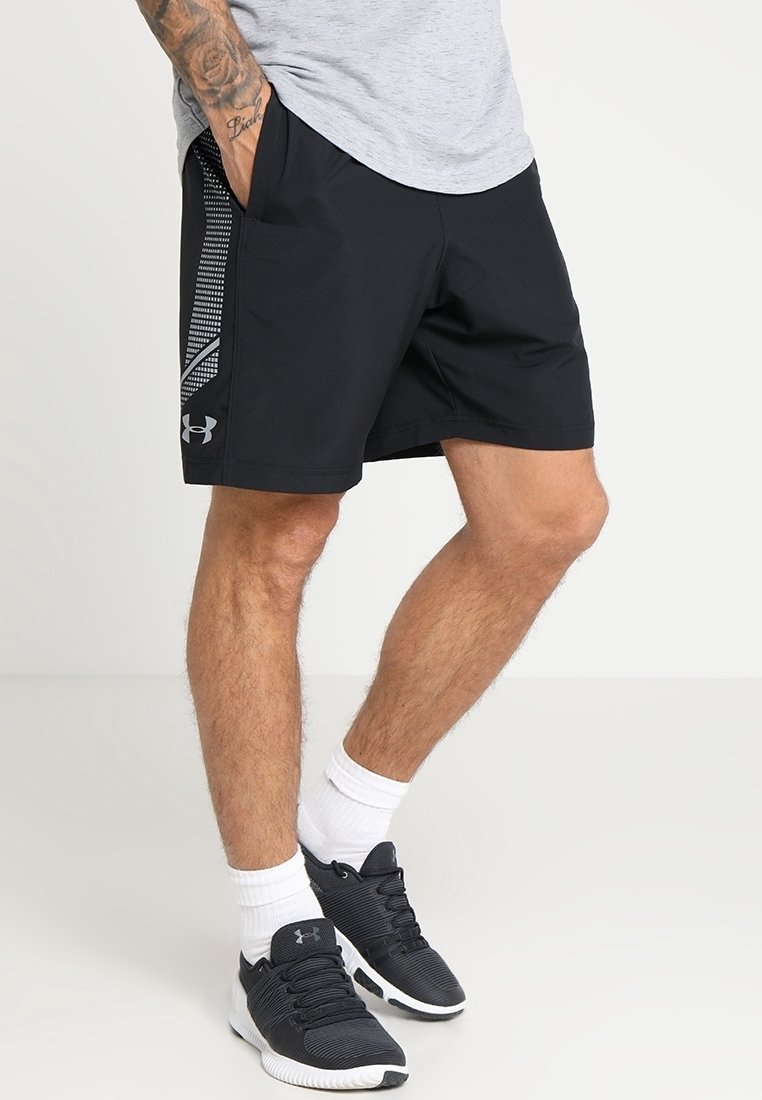 Svarta träningsshorts med ett mesh-mönster på sidan, tillverkade av lätt material. Bärs med vita strumpor och svarta träningsskor.