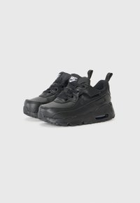 Sapatilhas Nike pretas com parte superior em couro, detalhes texturizados, design de atacadores e uma unidade de amortecimento de ar visível na sola.