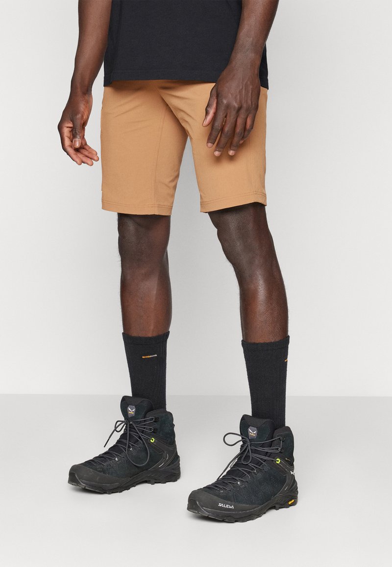 Beiga shorts av lätt material med sydda sömmar. Kombineras med svarta vandringskängor och ribbade svarta strumpor.