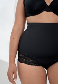 Højtaljede sorte trusser lavet af glat stof med blonde detaljer i siderne, med et sømløst design og en blød tekstur.