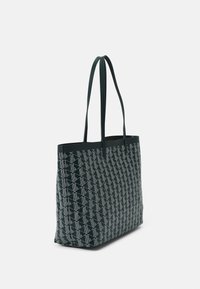 Sac fourre-tout avec un corps vert foncé, motif géométrique blanc, doubles poignées, forme rectangulaire, texture lisse et design à ouverture large.