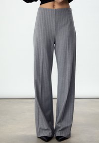 Grijze wijde broekspijpen met krijtstreep en een hoge taille. Zachte stoftextuur en een op maat gemaakt ontwerp, gecombineerd met zwarte pumps met spitse neus.