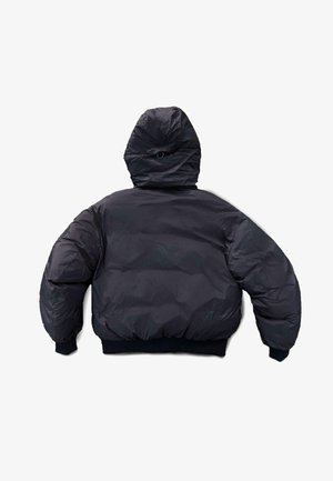 Melnā pūkaina jaka ar kapuci, ar dūraiņotu tekstūru, apjomīgu formu, elastīgām aprocēm un vidukļa siksnu, piemērota aukstam laikam.