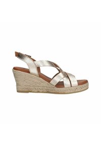 Metallisch silberne Keilsandalen mit gekreuzten Riemen, gewebter Jute-Zwischensohle und braunem Fußbett. Verstellbarer Knöchelriemen für einen sicheren Sitz.