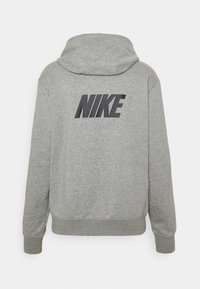 Šedá mikina s kapucí, dlouhými rukávy a strukturovaným povrchem. Na zadní straně se nachází výrazné černé logo "NIKE".