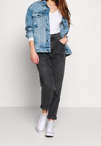 Denim jacket vaaleansinisena, valkoinen V-pääntie t-paita, tummanharmaat käärityt farkut ja valkoiset korkeavartiset tennarit. Rennon tyylikäs asu kerroksellisilla materiaaleilla.