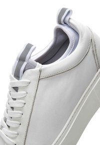 Baskets en cuir blanc avec une tige lisse, un bout rond, des accents gris contrastés, des lacets et une languette de maintien à l'arrière.
