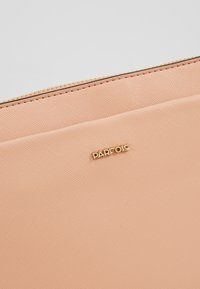 Pochette en cuir beige texturé avec une fermeture éclair dorée et un petit logo de marque "PARFOIS" doré centré sur le devant.