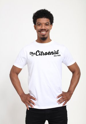 Witte katoenen t-shirt met zwarte tekst "The Citroënist Est. 1919" in een vet, cursief lettertype. Korte mouwen en een standaard ronde hals.