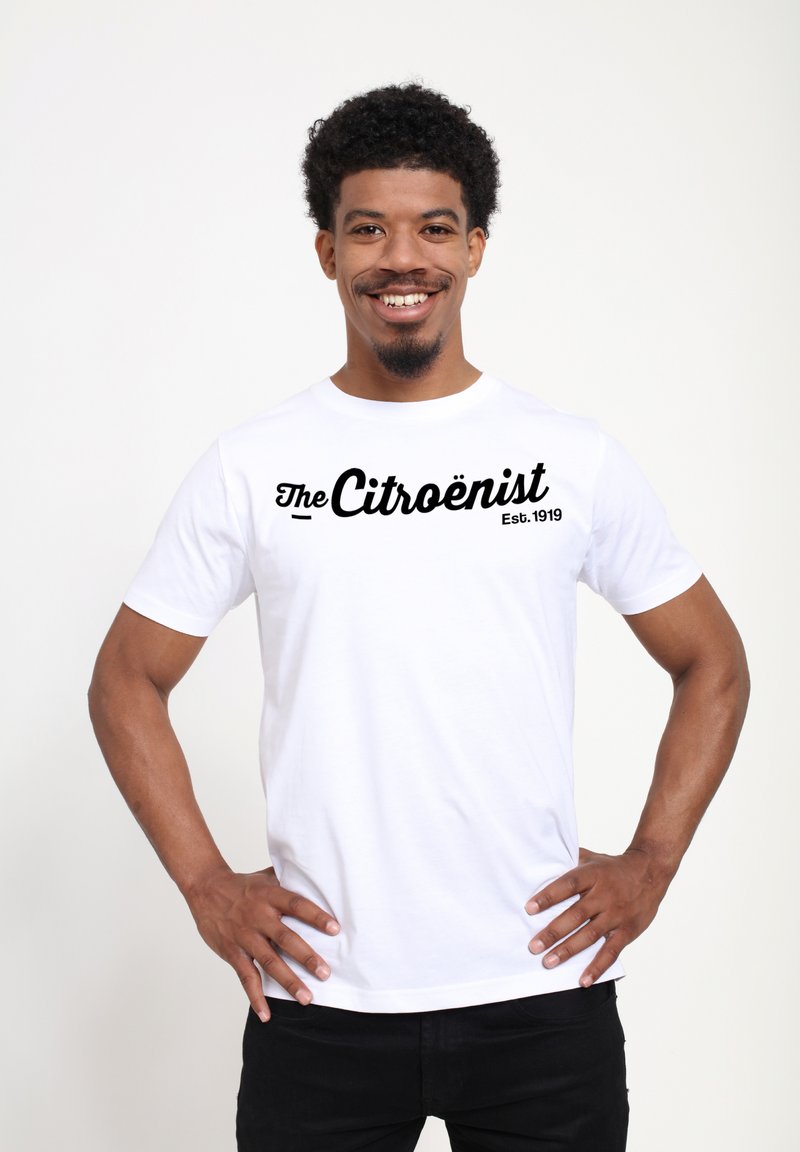 Bílý bavlněný tričko s černým textem "The Citroënist Est. 1919" ve výrazném kurzívním písmu. Krátké rukávy a standardní kulatý výstřih.
