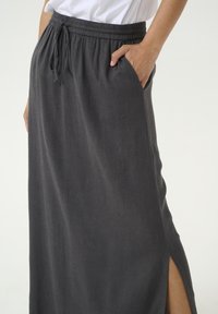 Gonna maxi in lino grigio scuro con vita regolabile, spacco laterale e tasche, caratterizzata da una texture morbida e un design traspirante.