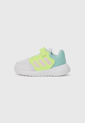 Zapatilla con parte superior de malla blanca, acentos en verde neón, rayas rosas, diseño ligero, correa de velcro y un talón texturizado en verde menta.