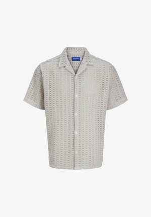 Krótki rękaw koszula zapinana na guziki w jasnym beżu z ażurowym wzorem. Posiada kołnierzyk w kształcie litery V oraz pięć guzików z przodu.