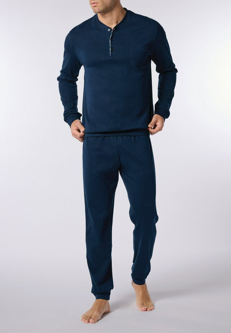 Completo da loungewear blu navy composto da una maglia henley a maniche lunghe con scollatura a bottoni e pantaloni affusolati abbinati, entrambi realizzati in morbido tessuto.