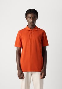 Oransje polo-skjorte laget av bomull, med klassisk krage, to-knapps placket, og ton-i-ton logo på brystet. Korte ermer.