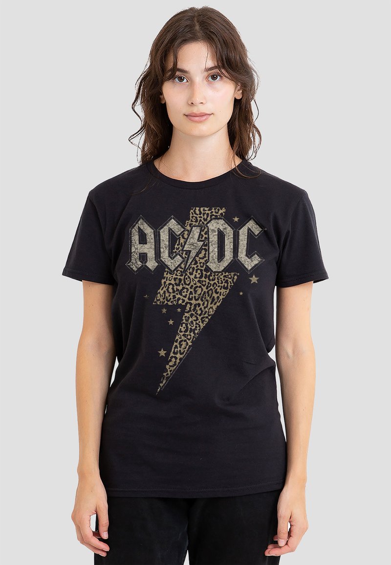 Schwarzes Baumwoll-T-Shirt mit Leopardenmuster und einem Blitz in Grau, dazu der Text "AC/DC" mit Sternakzenten. Kurze Ärmel und Rundhalsausschnitt.