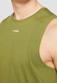 Oliwkowy bezrękawnik sportowy wykonany z gładkiego materiału. Posiada okrągły dekolt oraz haftowane białe logo Pumy na piersi.