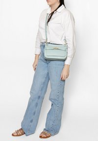 Borsa a tracolla in pelle verde menta con forma rettangolare, accessori in ottone e superficie testurizzata. Cinghia regolabile e pattina superiore con chiusura.