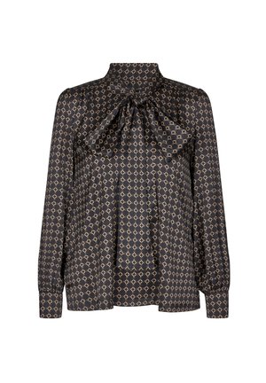 Blouse noire à manches longues avec motif chaîne géométrique beige et grand nœud noué au cou, avec poignets boutonnés.