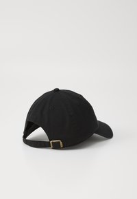 Căciulă de baseball din bumbac negru, cu o margine curbată, curea ajustabilă la spate și detaliu cu cataramă metalică. Textură netedă, fără logo-uri sau modele vizibile.