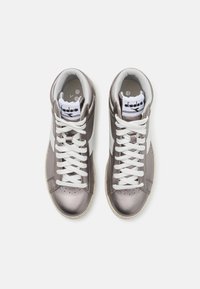 Baskets montantes en gris métallique avec des accents et des lacets blancs. Texture lisse avec des perforations sur l'orteil et une languette de marque.