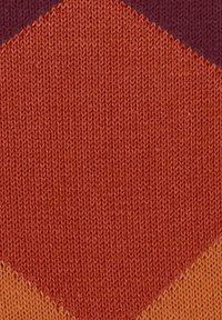 Tessuto testurizzato caratterizzato da una calda palette di colori, con tonalità di rosso e arancione, e un motivo a diamante ripetuto sulla superficie.