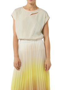 Jasno beżowa bluzka z dekoltem łódką i wycięciem, w zestawieniu z plisowaną spódnicą, która przechodzi z bieli w żółć na końcu.