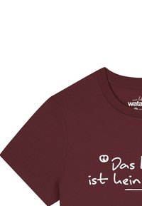 Burgunderfarbendes Baumwoll-T-Shirt mit kurzen Ärmeln, mit weißem Text: "Das ist kein." Runder Halsausschnitt und weiche Textur.
