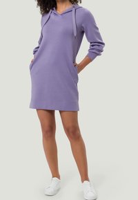 Robe sweat à capuche violet avec manches longues, poches kangourou et capuche avec cordon. Le tissu semble doux et lisse, se terminant au-dessus du genou.