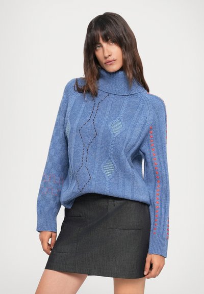 Maglione lavorato a maglia blu chiaro con un alto colletto, caratterizzato da motivi testurizzati e dettagli di cucitura rossa sulle maniche, abbinato a una gonna scura.