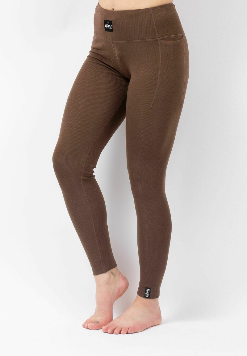 Brown leggings with a ribbed texture, high waistband, and side pocket. Features a small black logo tag on the left ankle.