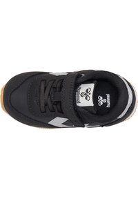 Scarpa sportiva nera con punta arrotondata, presenta una parte superiore texturizzata, dettagli grigi, una striscia in Velcro e una suola in gomma color caramello.