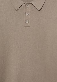 Beige polo tričko vyrobené z měkké pleteniny, s límečkem a tříknoflíkovým zapínáním s odpovídajícími knoflíky. Hladký povrch, ležérní design.