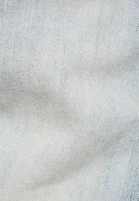 Tela de denim azul claro que muestra una textura suave con un sutil patrón de sarga y ligeras variaciones en la profundidad del color.