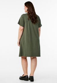 Olive green cotton blend dress with short sleeves, a relaxed fit, and knee-length hem. Details include side pockets and a smooth texture.