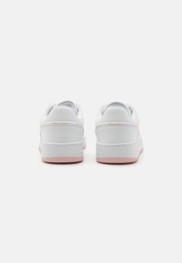 Zapatillas de cuero blancas con una textura suave, que presentan una suela de goma rosa y acentos. Tacón redondeado con un detalle de costura mínimo.