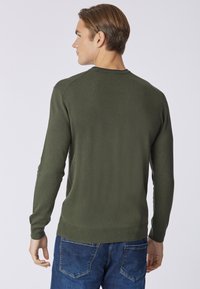 Maglione lavorato a maglia verde oliva con maniche lunghe, scollatura e polsini a coste, design della schiena senza cuciture, indossato con jeans blu.