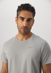 T-shirt Nike gris clair fabriqué à partir d'un tissu doux et respirant. Comprend un col rond et un petit logo imprimé sur la poitrine gauche.