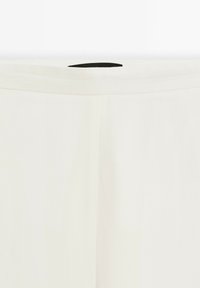 White fabric pants with a clean design. Smooth texture and straight shape. Features a black inner tag at the waistband.