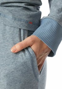 Light blue heathered sweatshirt with ribbed cuffs and a side pocket. Soft fabric with a relaxed fit and contrasting stitching details.