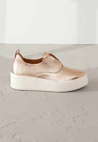 Baskets à enfiler en métal rose doré avec un dessus texturé, des inserts élastiques et une semelle plateforme blanche épaisse.