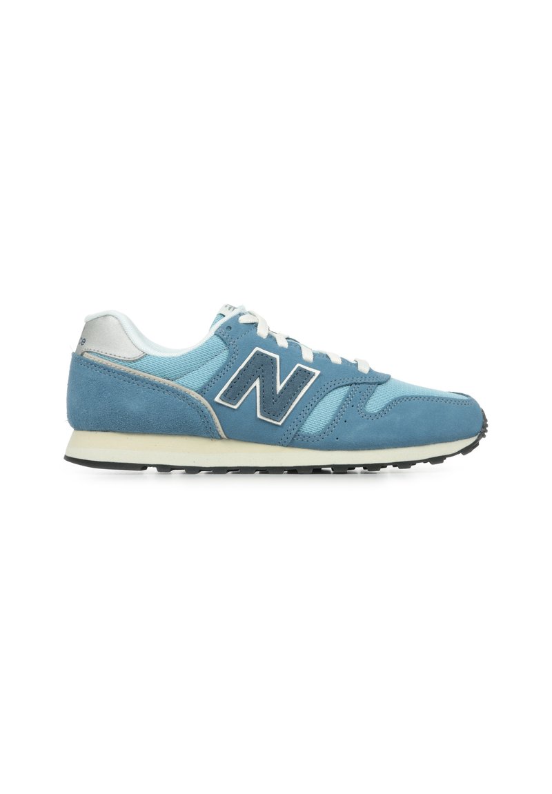 Chaussure de sport bleue avec un dessus en daim et en maille, lacets blancs, un grand logo "N" bleu marine et une semelle en caoutchouc noir.