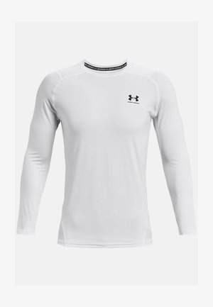 Chemise de sport à manches longues blanches en tissu lisse. Elle présente un col rond et un logo noir à l'avant. Les coutures mettent en valeur le design.