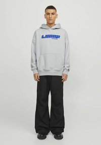 Sudadera gris con un logo azul "LUNAR JACK & JONES", con un bolsillo canguro y puños de canalé, combinada con pantalones anchos negros.