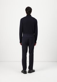 Navy turtleneck sweater paired with tailored trousers. Fitted design, soft texture, and sleek black shoes. Minimalist style, no visible patterns.