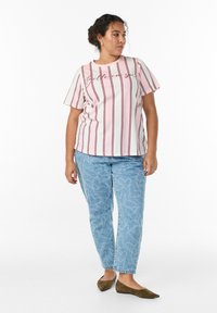 White t-shirt with burgundy vertical stripes and text, paired with light blue jeans featuring heart patterns and brown flats.