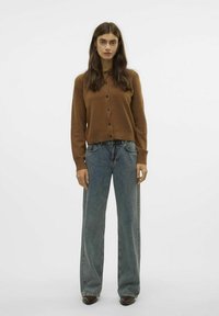 Brun knappad cardigan i mjukt material, ihopparad med högmidjade, vida blå jeans med diskret blekning och kontrasterande sömmar.