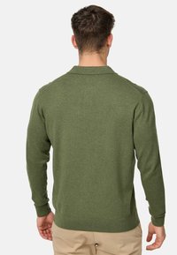 Jersey verde de punto con cuello, puños acanalados y dobladillo. La tela tiene una textura suave, con un diseño ajustado y un detalle mínimo.